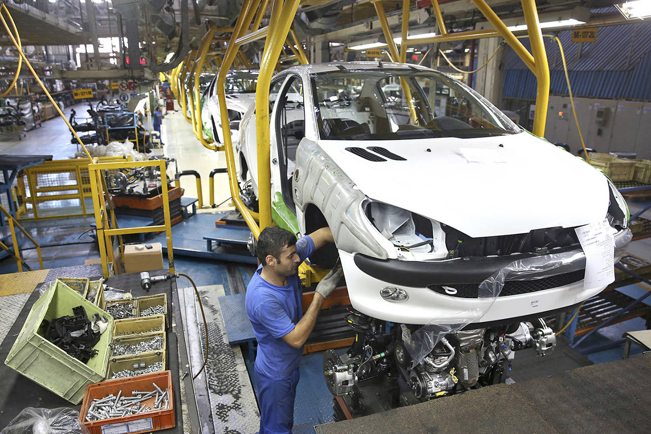 In this 2014 photo, an Iranian worker assembles a Peugeot 206 at the state-run Iran-Khodro automobile manufacturing plant near Tehran, Iran. (AP Photo/Ebrahim Noroozi, File)