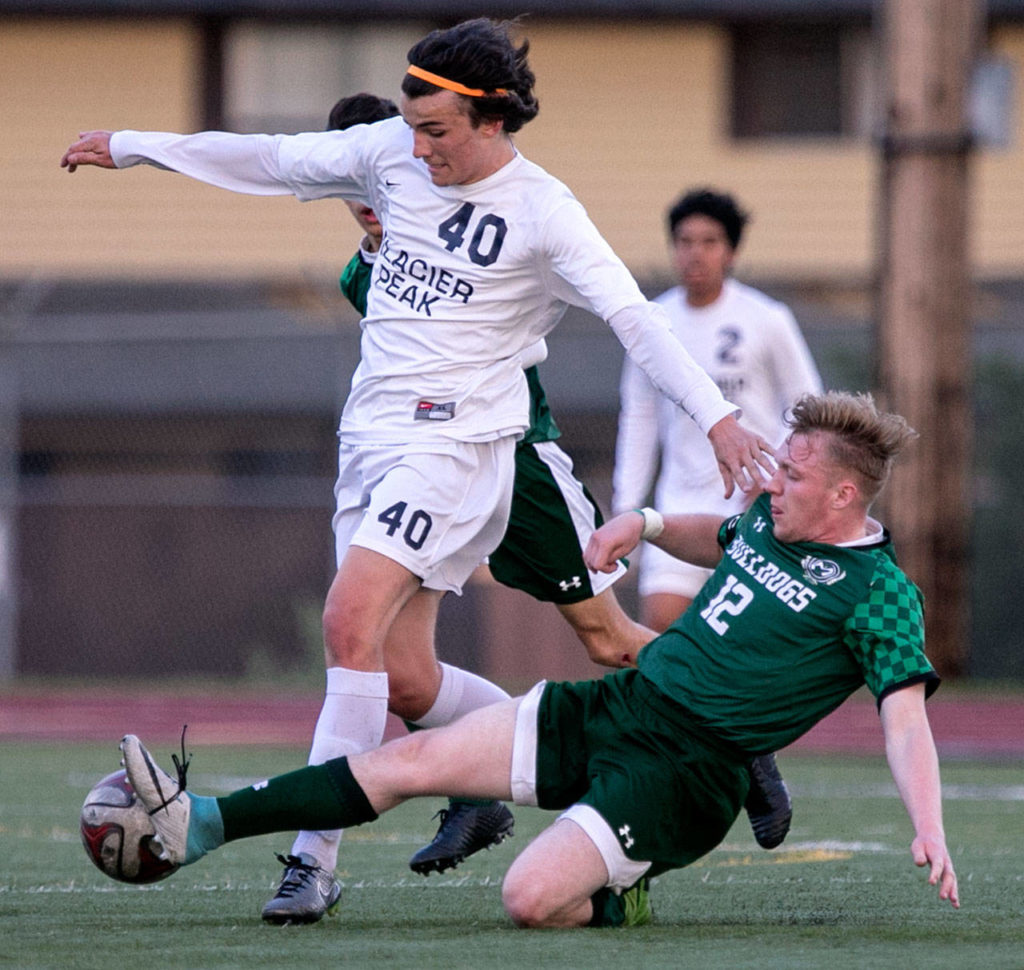 Mount Vernon’s Dakota Stamnes slides in for a challenge on Glacier Peak’s Keegan Rubio during the 4A district championship Thursday at Goddard Stadium in Everett. Rubio scored two goals in the Grizzlies’ 3-0 win. (Kevin Clark / The Herald)
