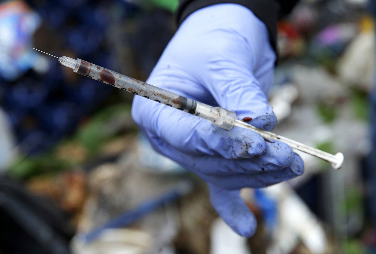 Steph Gaspar, a volunteer outreach worker with The Hand Up Project, an addiction and homeless advocacy group, holds a used and blood-filled needle used for drug injection that she found while cleaning up a homeless encampment in Everett, in November, 2017. The Aids Outreach syringe exchange program in Everett encourages the safe disposal of needles by offering a one-to-one exchange for clean syringes. (Ted S. Warren/Associated Press file photo)