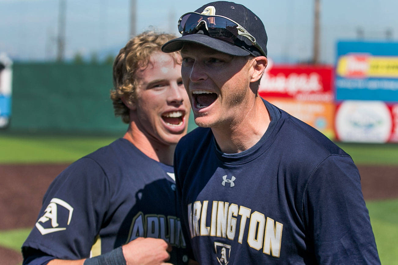 Arlington’s Gavin York (left) and Scott Striegel, Arlington’s head coach, celebrate their win for the 3A district third-place game against Meadowdale Saturday afternoon at Everett Memorial Stadium Everett on May 12, 2018. (Kevin Clark / The Herald)