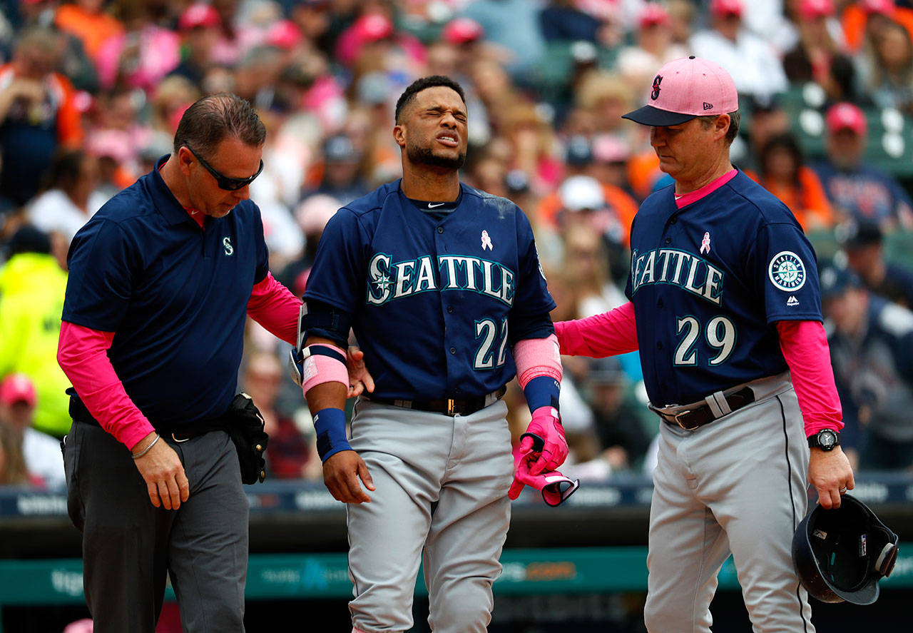 Robinson Cano of the Seattle Mariners (22) grimaces while being attended to by trainer Rob Nodine (left) and manager Scott Servais after being hit in the hand by a pitch from Detroit’s Blaine Hardy in the third inning of Sunday’s game in Detroit. (AP Photo/Paul Sancya)