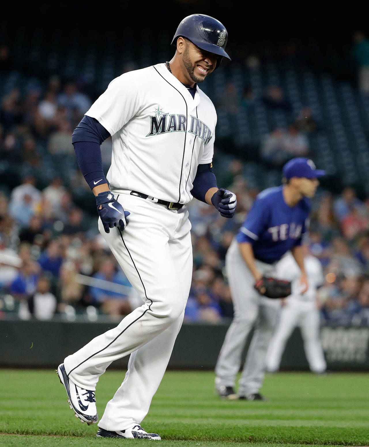 The Mariners’ Nelson Cruz (left) limps toward first base after being hit in the foot by a pitch from the Rangers’ Brandon Mann (right) during a game on May 15, 2018, in Seattle. (AP Photo/Elaine Thompson)