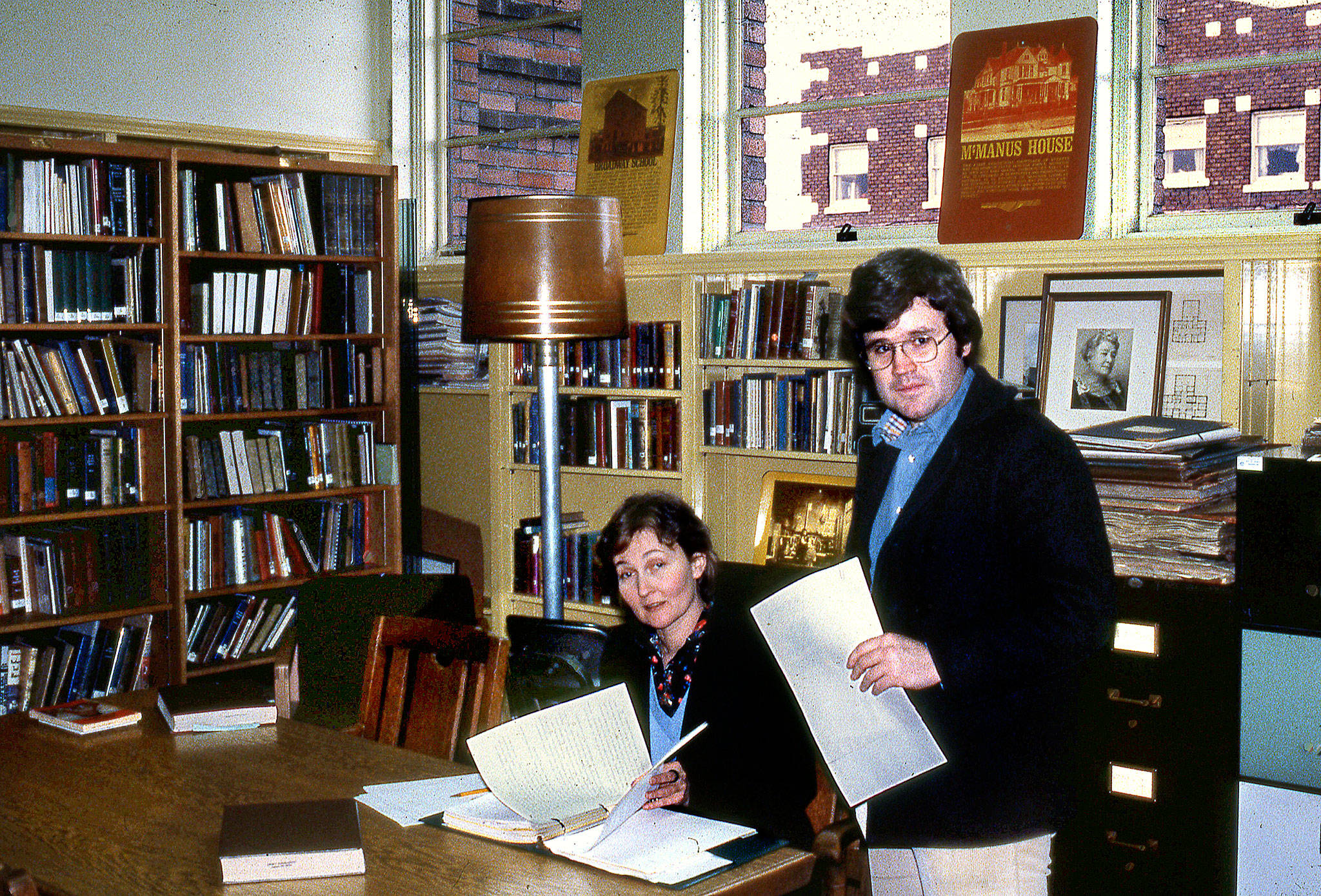 Historians David Dilgard and Margaret Riddle, who started at the Everett Public Library in 1977, are shown in the early days of their careers in a space now used to sort books. Riddle retired in 2008. Dilgard’s last day on the job was March 22, 40 years after he and Riddle started at the library. Together they worked to create the library’s Northwest Room. (Everett Public Library photo)