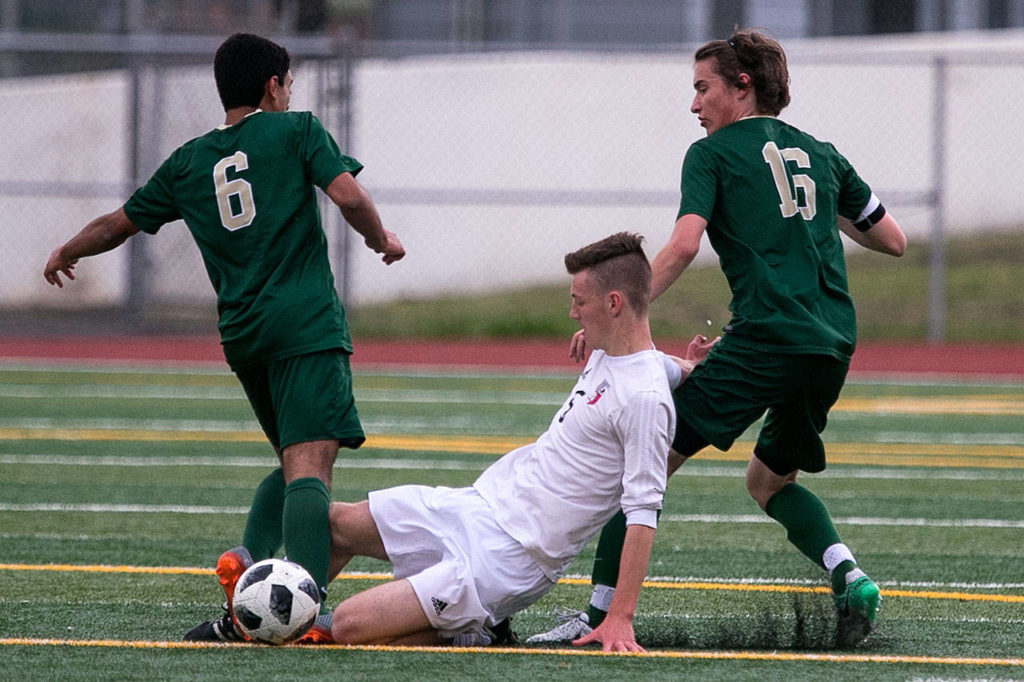 Snohomish’s Liam Raney (center) slides to dislodge the ball from Redmond’s Victor Araujo (left) with Redmonds’ Jacen Stein trailing during a state quarterfinal match on May 18, 2018, at Veterans Memorial Stadium in Snohomish. (Kevin Clark / The Herald)
