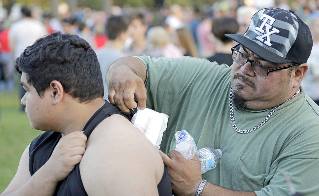 Gabriel San Miguel (right) removes a bandage from his son’s back after attending a prayer vigil following a shooting at Santa Fe High School in Santa Fe, Texas, on Friday. The boy, a Santa Fe High School student named Abel San Miguel, was inside a classroom when a gunman opened fire. (AP Photo/David J. Phillip)
