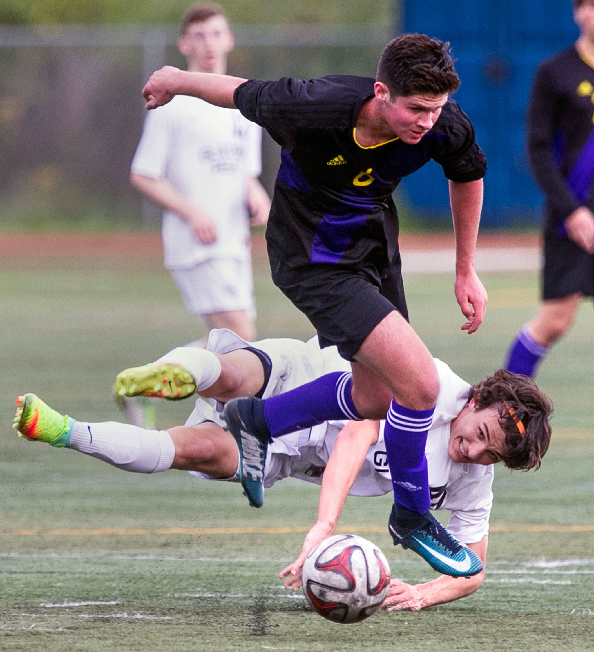 Sumner’s Mitchell Hutter (front) leaps over Glacier Peak’s Keegan Rubio during a boys state soccer quarterfinal match on May 19, 2018, at Glacier Peak High School in Snohomish. (Kevin Clark / The Herald)