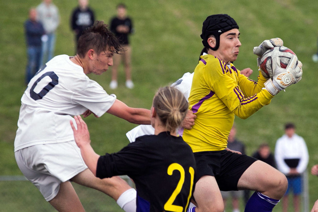 Sumner’s Alex Pagonis (right) makes a save with Glacier Peak’s Cade Turner (left) and Sumner’s Zachery Prenovost battling for position during a boys state soccer quarterfinal match on May 19, 2018, at Glacier Peak High School in Snohomish. (Kevin Clark / The Herald)
