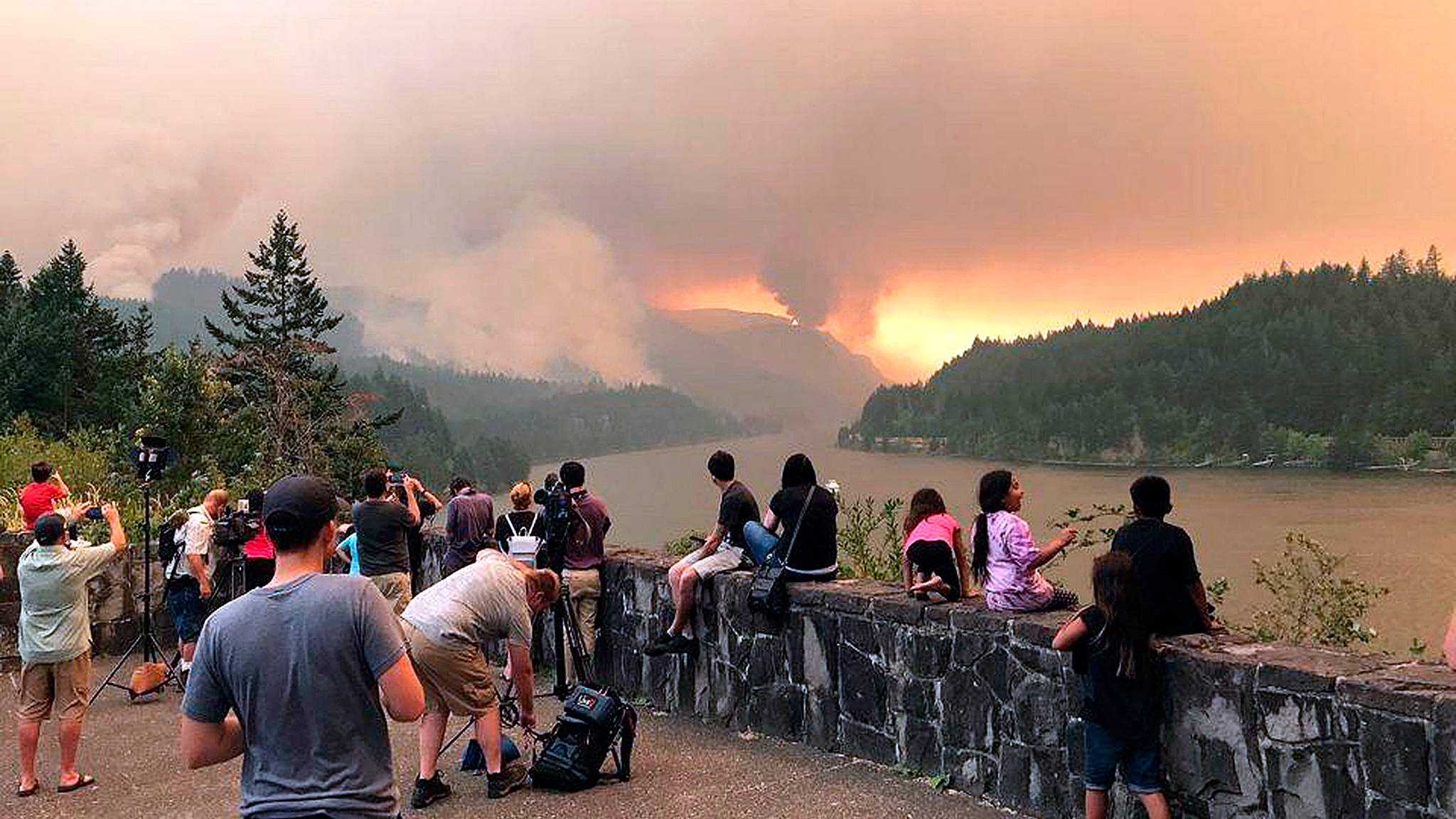 This Sept. 4, 2017, photo shows people at a viewpoint overlooking the Columbia River watching the Eagle Creek wildfire burning in the Columbia River Gorge east of Portland. (Inciweb via AP)