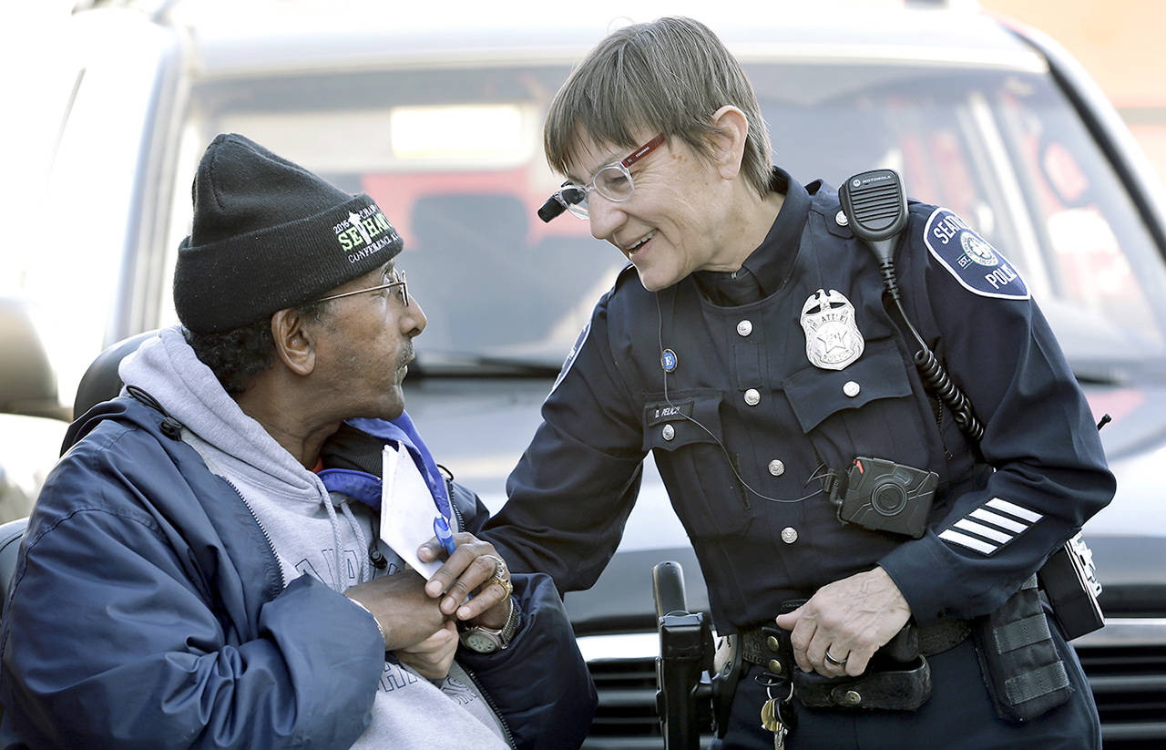 In this March 2015 photo, Seattle police officer Debra Pelich (right) wears a video camera on her eyeglasses as she talks with Alex Legesse before a small community gathering in Seattle. (AP Photo/Elaine Thompson, File)