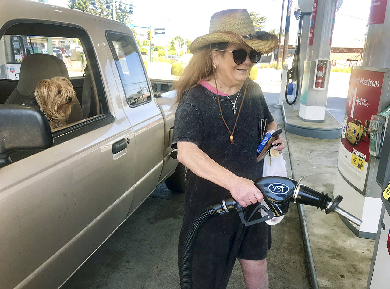 Kerri Clark, of Everett, under the watchful eye of her terrier, Chewie, fills up her Ford pickup for her Memorial Day weekend fun at Blackmans Lake in Snohomish to do some fishing. Regular gas at Forest Park Chevron at Rucker Avenue and 41st Street was going for $3.49 a gallon Wednesday. She wanted to fill up early to beat the lines and any rise in gas prices. (Andrea Brown / The Herald)