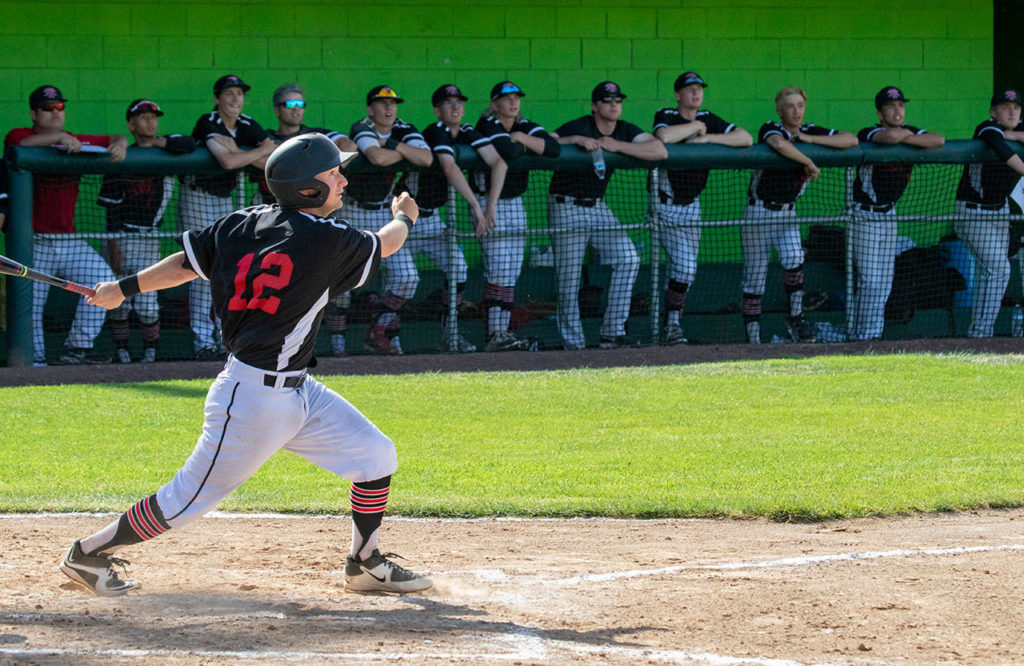 Mountlake Terrace’s Layne Zuschin (12) hits a fly ball as the team watches against Ellensburg during the 2A state baseball championship game on May 26, 2018, in Yakima. Ellensburg defeated Mountlake Terrace 2-1. (TJ Mullinax/For The Herald)
