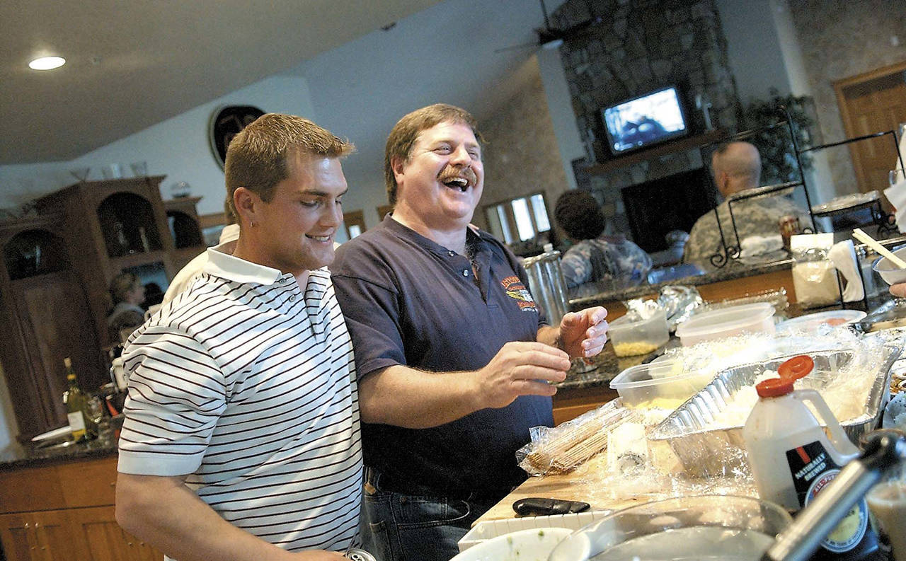 In this 2006 photo, Capt. Rick Quashnick (right) shares a laugh with boat engineer Blake Painter (left) as family and close friends gather at Quashnick’s Warrenton, Oregon, house to watch the Discovery Channel series “The Deadliest Catch.” (Lori Assa/Daily Astorian via AP, File)