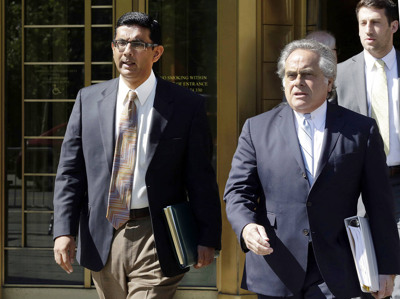 In this May 20, 2014 photo, conservative scholar and filmmaker Dinesh DSouza (left) accompanied by his lawyer Benjamin Brafman leaves federal court, in New York. (AP Photo/Richard Drew)