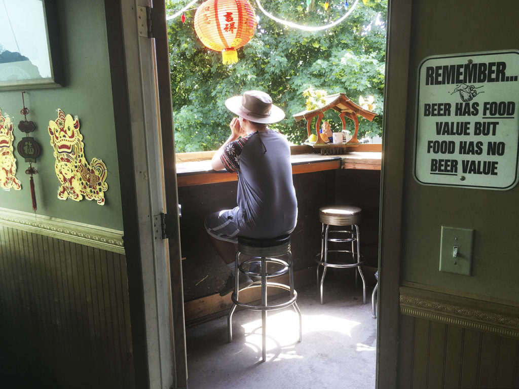 Khoa Nguyen, of Everett, waits for his lunch order of pineapple fried rice on the outdoor patio overlooking the railroad tracks at the Riverview Market & Cafe in Everett on Wednesday. (Sue Misao / The Herald)
