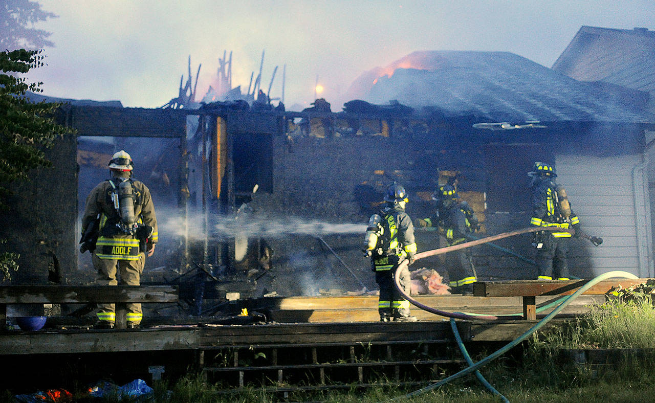 Firefighters pour water on hot spots after a fire burned a house on the north side of Snohomish on Friday morning. (Doug Ramsay for The Herald)