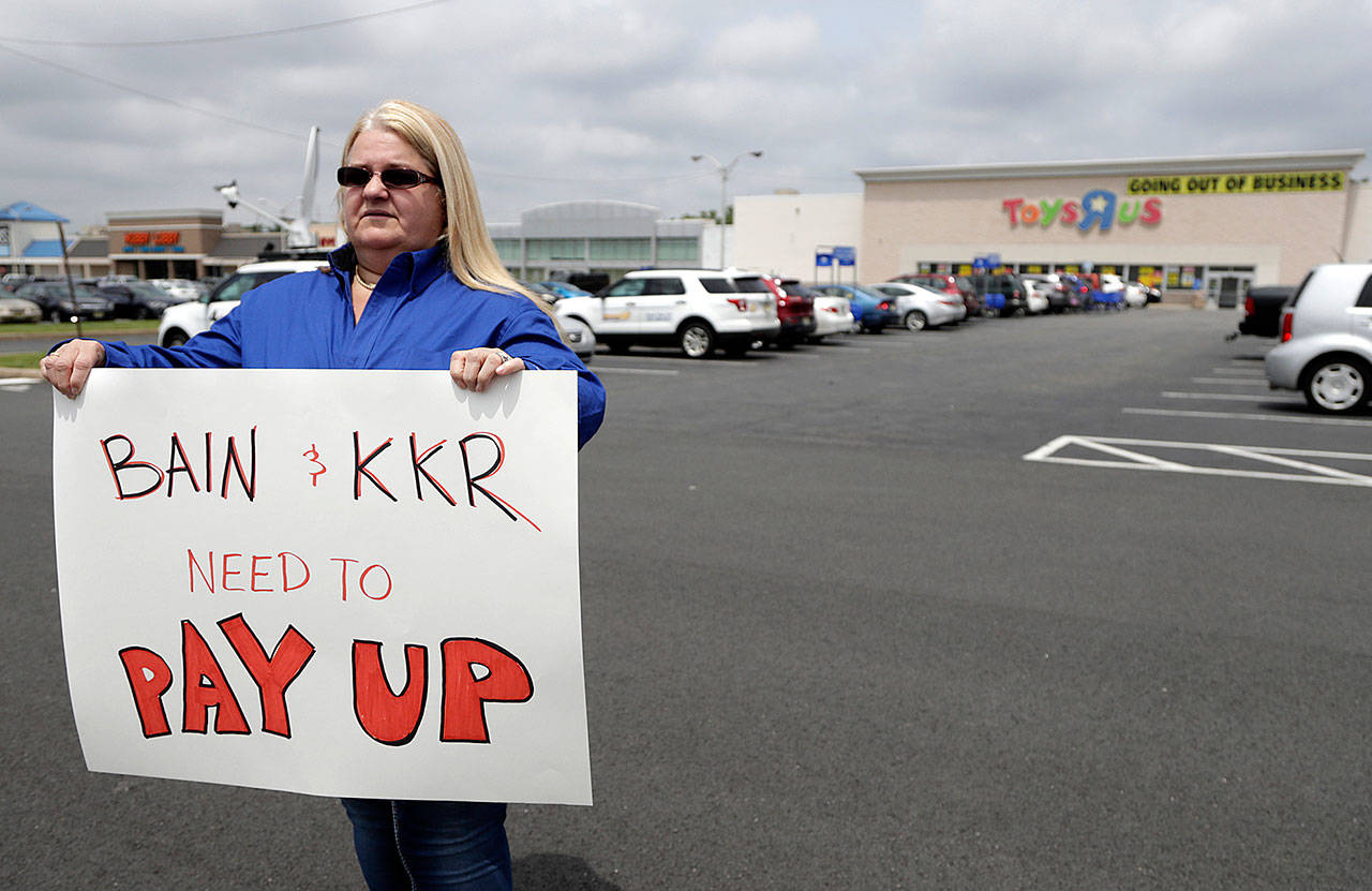 Cheryl Claude, an assistant manager at the Toys R Us store in Woodbridge, New Jersey, holds a sign in front of the Totowa location before a news conference with politicians Friday. (AP Photo/Julio Cortez)