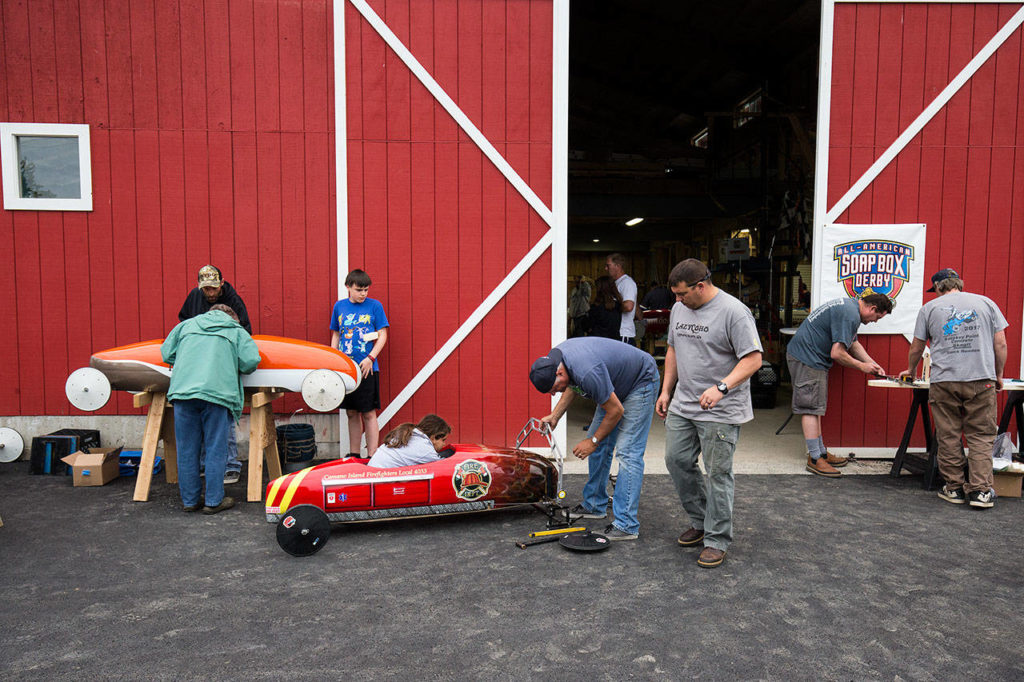 Parents and kids prep soap box derby cars outside the barn. (Andy Bronson / The Herald)
