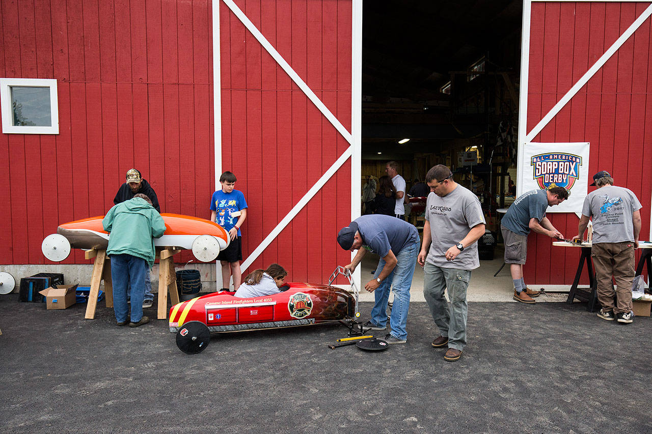 Parents and kids prep soap box derby cars outside the barn. (Andy Bronson / The Herald)