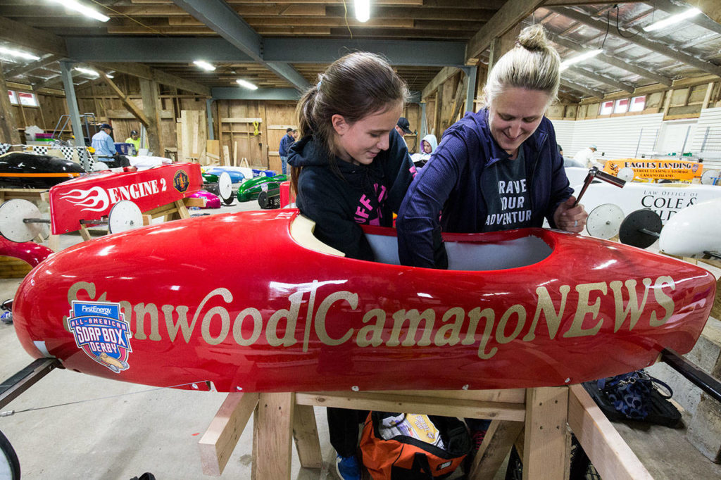 First year driver Charlotte McNeely, 13, and her mother, Stephanie, work their Super Stock soap box derby car brakes at the barn. (Andy Bronson / The Herald)
