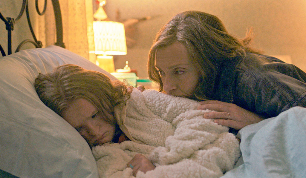 Odd duck daughter Milly Shapiro is consoled by mom Toni Collette in a scene from “Hereditary.” (A24)
