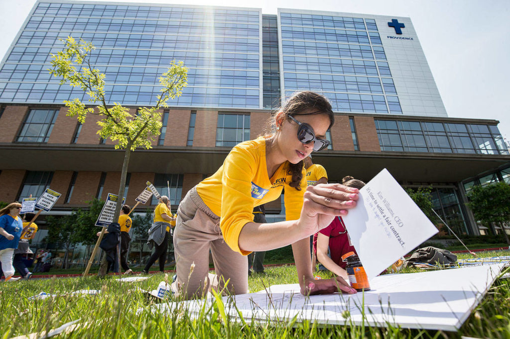 UFCW organizer Graciela Nune, affixes cards address to various administrators on a board as nurses with UFCW 21 and their supporters picket at Providence Regional Medical Center Everett on Wednesday. The boards, with notes pleading for a contract settlement, are to be presented to the administrators tomorrow. (Andy Bronson / The Herald)
