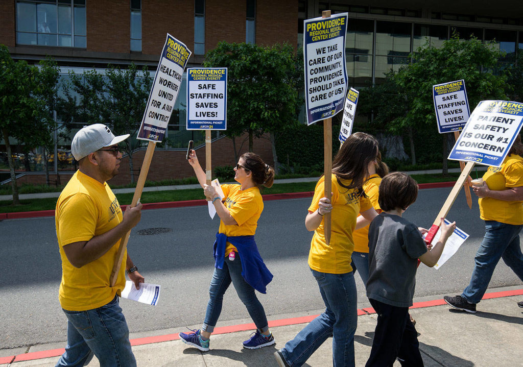 Nurse Amber Palermo, a member UFCW 21, takes video of picketers and their supporters outside at Providence Regional Medical Center Everett on Wednesday. (Andy Bronson / The Herald) 
