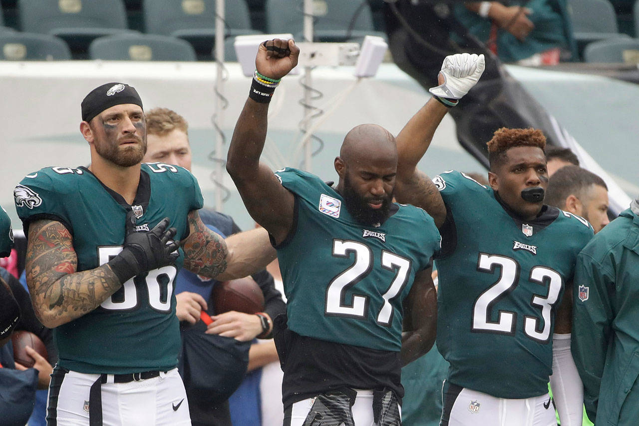 The Eagles’ Chris Long (56), Malcolm Jenkins (27) and Rodney McLeod (23) gesture during the National Anthem before a game against the Cardinals on Oct. 8, 2017, in Philadelphia. (AP Photo/Matt Rourke)