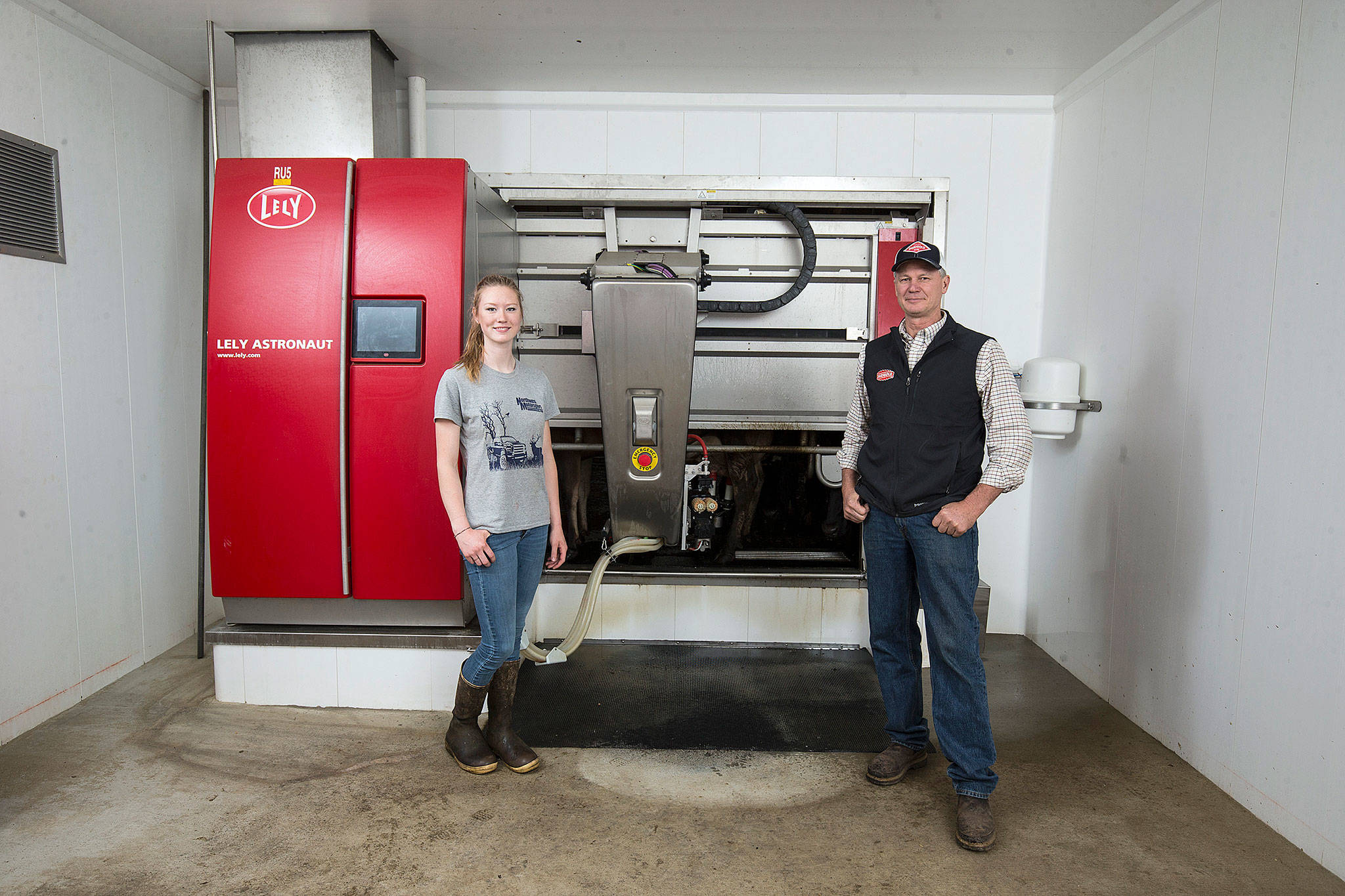 Paradise Jerseys owner Leroy Plagerman and daughter Jana in front of one of eight automated milking machines at their dairy in Ferndale. (Andy Bronson / The Herald)
