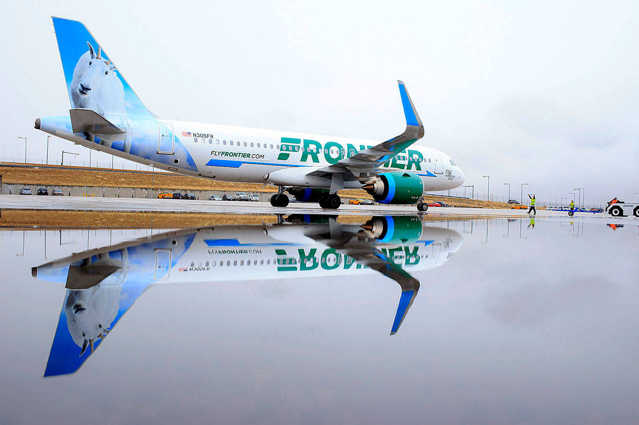 A Frontier Airlines plane is reflected in a puddle on the tarmac at Denver International Airport. (Matthew Staver / Bloomberg)