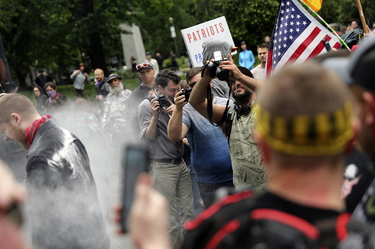 In this June 3 photo, photographers capture dueling demonstrations between antifacists known as antifa and a right wing group called Patriot Prayer in downtown Portland, Oregon. (Mark Graves/The Oregonian via AP, file)