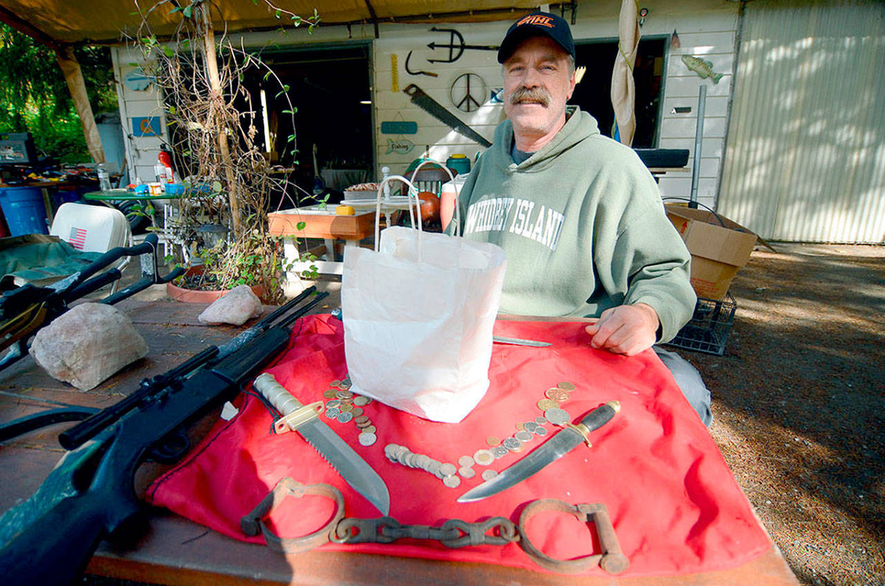 Clinton resident John Norris poses last fall with some of the items he found in an abandoned storage unit he purchased. He also found the white sack, which contained what was later determined to be a human skull. (Justin Burnett / South Whidbey Record)