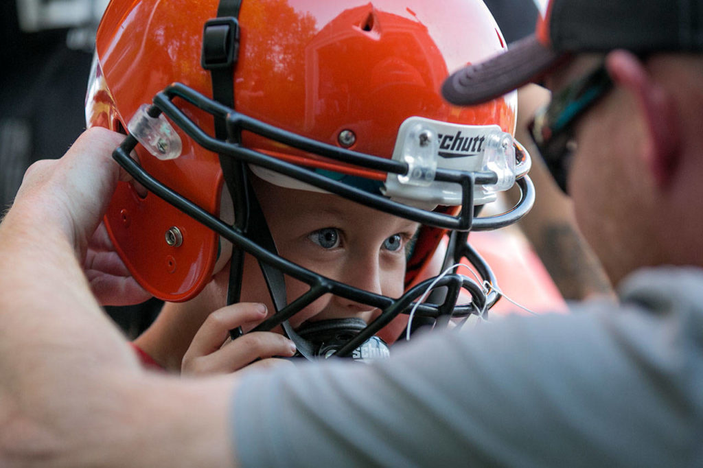 Tate Bain, 4, (left) is fitted for a helmet by Dave Anderson at Granite Falls High in Granite Falls on June 6, 2018. (Kevin Clark / The Herald)
