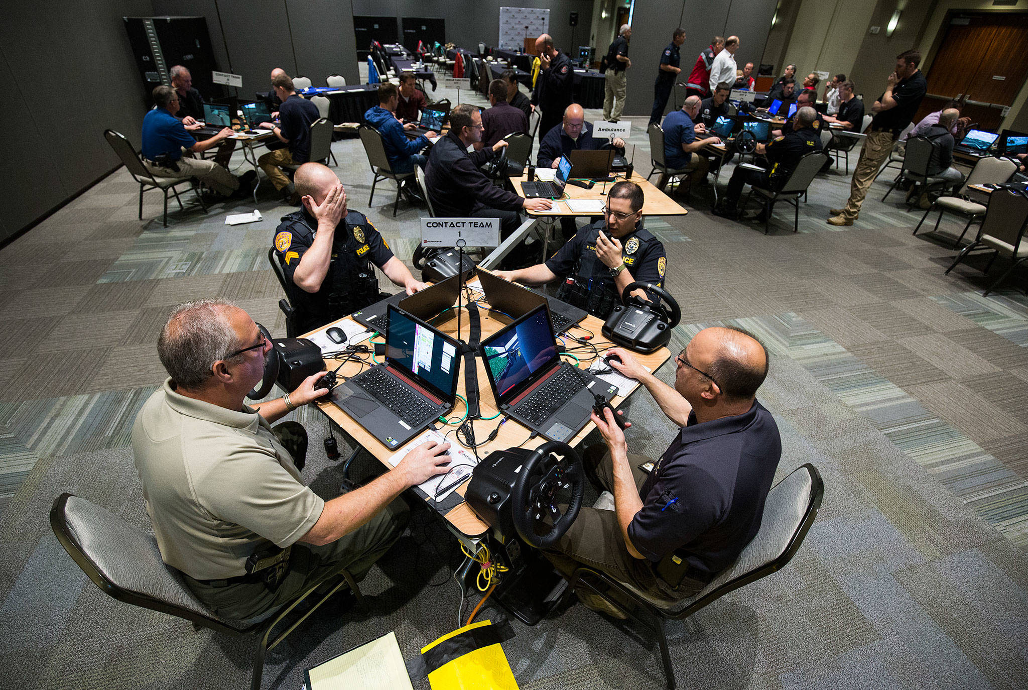 Law enforcement officers, firefighters and medics from Snohomish, King and Pierce counties use computers to simulate an active shooter scenario in a ballroom at Angel of the Winds Arena on Wednesday in Everett. (Andy Bronson / The Herald)