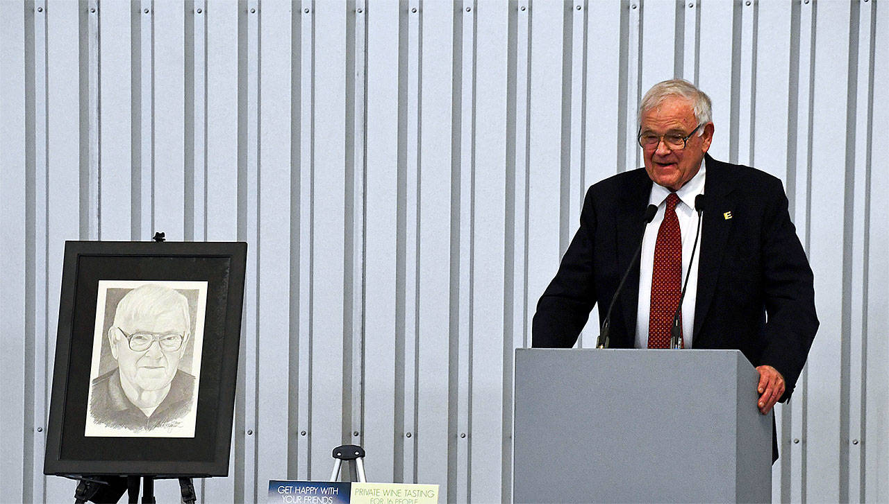 John Osterhaug accepts the 2018 E Award alongside a portrait created by Michael Reagan at the Edmonds Senior Center annual gala and auction, held May 5 at the Museum of Flight. (Contributed photo)