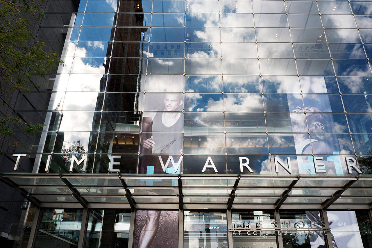 In this 2016 photo, clouds are reflected in the glass facade of the Time Warner building in New York. (AP Photo/Mark Lennihan, File)