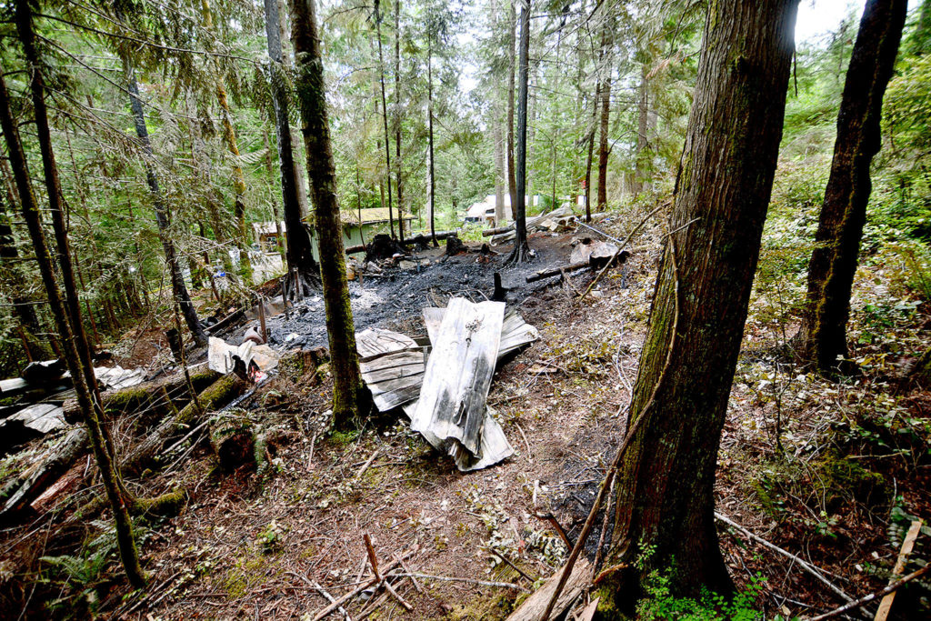 The remains of a cabin that exploded and burned in Brinnon, Jefferson County, where family of five from Monroe died on Sunday. (Jesse Major / Peninsula Daily News)
