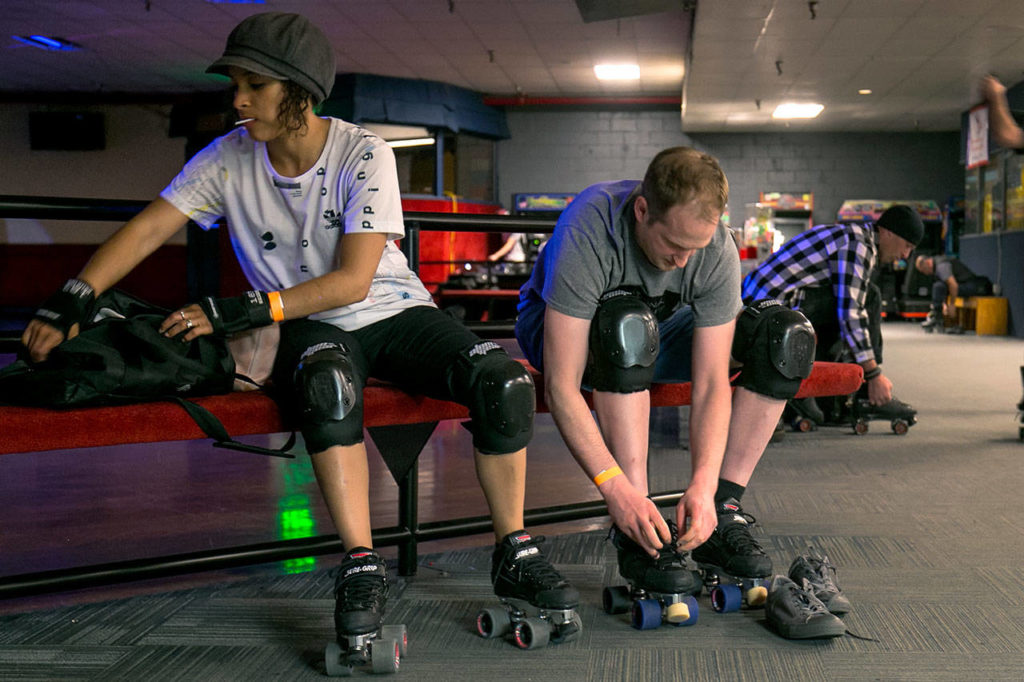 Dawn Johnston (left) and Oliver Loud gear up Thursday night during Adult Open Skate at Lynnwood Bowl and Skate in Lynnwood on June 14, 2018. (Kevin Clark / The Herald)
