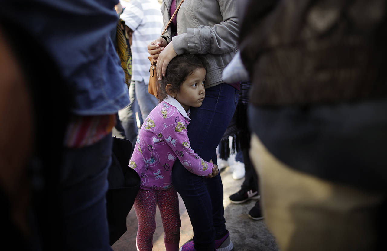 In this June 13 photo, Nicole Hernandez, of the Mexican state of Guerrero, holds on to her mother as they wait with other families to request political asylum in the United States, across the border in Tijuana, Mexico. (AP Photo/Gregory Bull)
