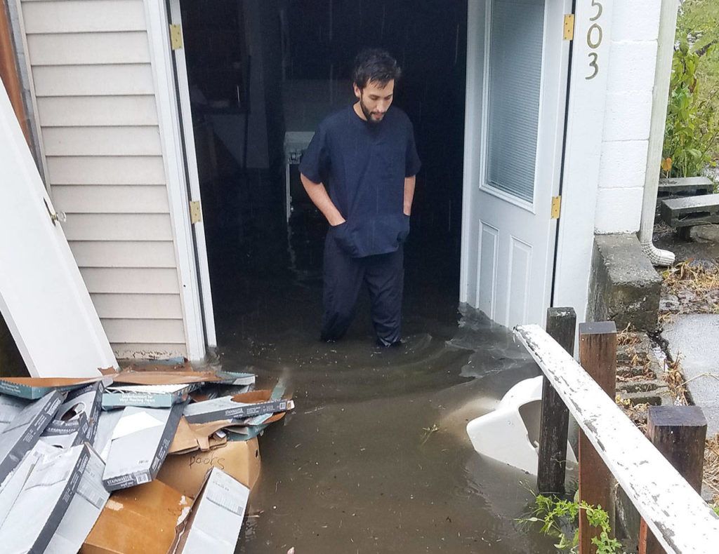 Tyler Denton wades through flood waters at his home in Everett. A newly renovated basement apartment was destroyed. (Courtesy photo)
