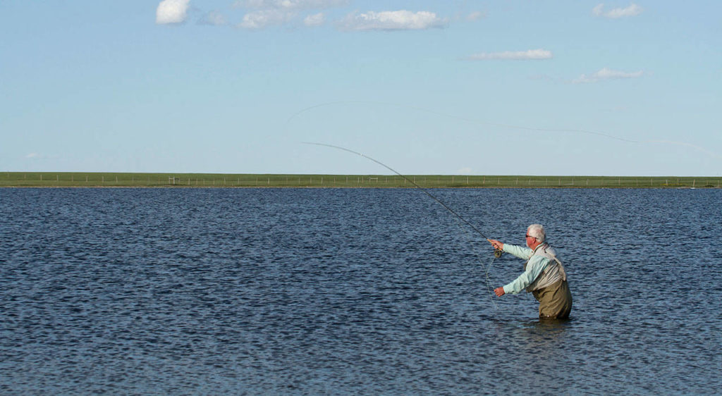 Dick Snow of Marysville casts for fish along the shoreline of Montana’s Mission Lake. (Photo by Mike Benbow)
