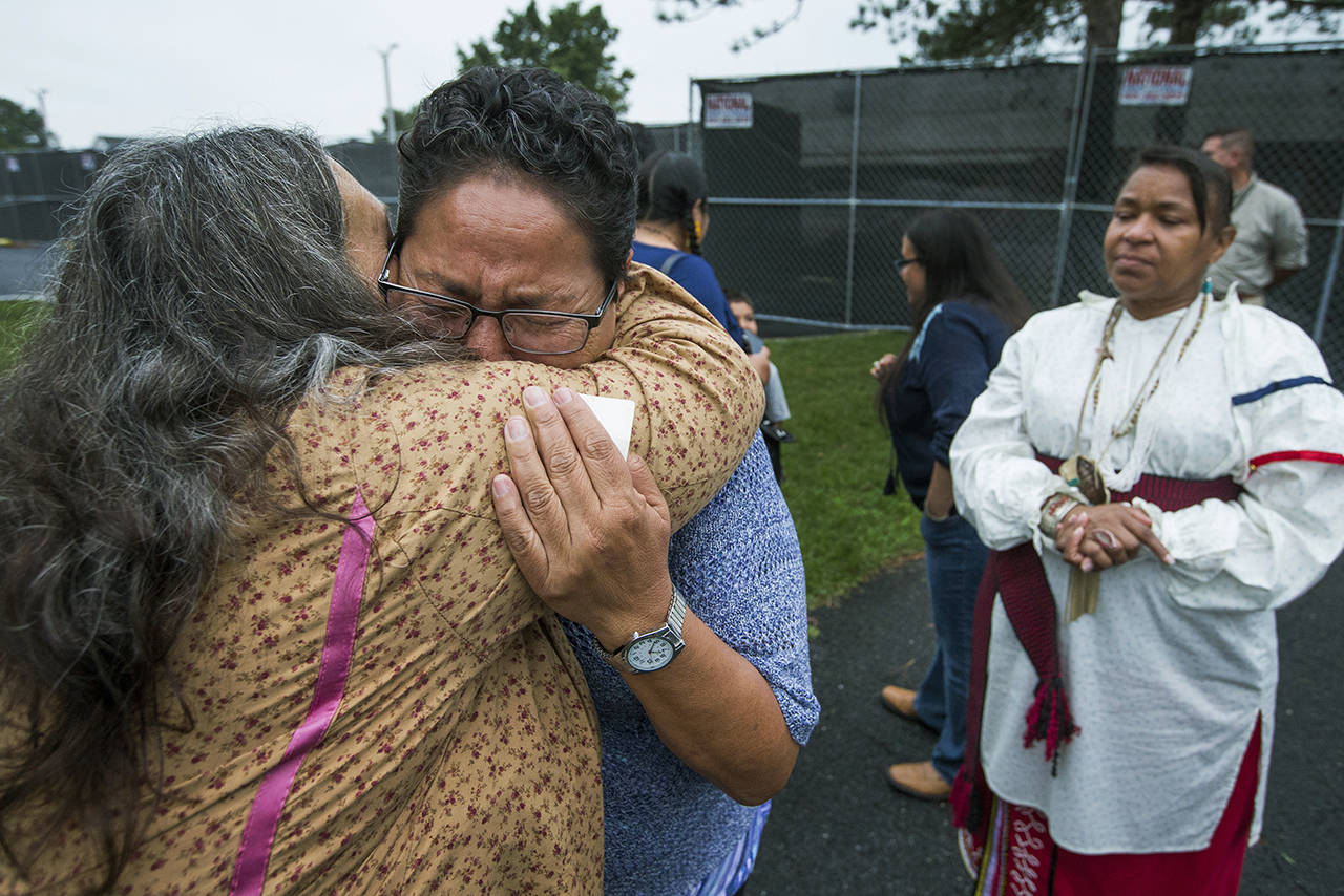In this Aug. 2017 photo, Millie Friday, a descendent of Little Plume, a Native American student who was taken from his family and forced to go to boarding school, is comforted by Barbara Andrews-Christy of Circle Legacy Center, as Aílice Hall looks during a gathering on the grounds of the Carlisle Barracks, in Carlisle, Pennsylvania. (Charles Fox/The Philadelphia Inquirer via AP, File)
