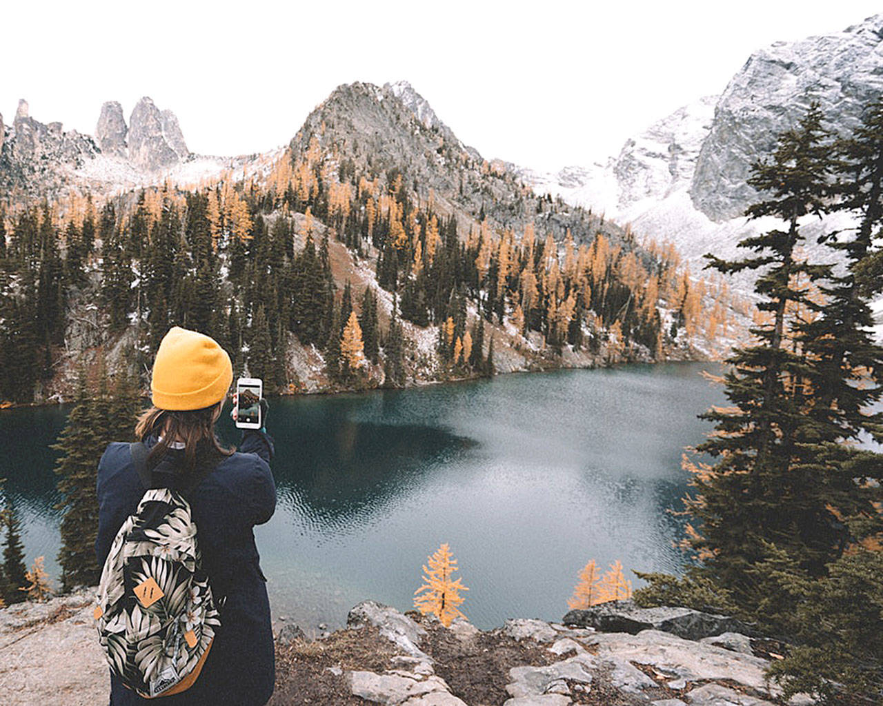 A hiker stops to take a photo with her cellphone in the North Cascades. (Unsplash)