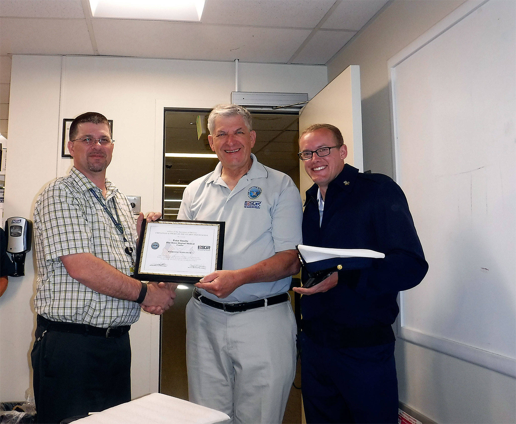 Peter Smeltz (left) accepts an Employer Support of the Guard and Reserve Patriot Award at the Snohomish Health District on Dec. 21 from ombudson John Van Dalen. Smeltz was nominated for the Patriot Award by U.S. Coast Guardsman Petty Officer Nat Lofton (right). (Contributed photo)