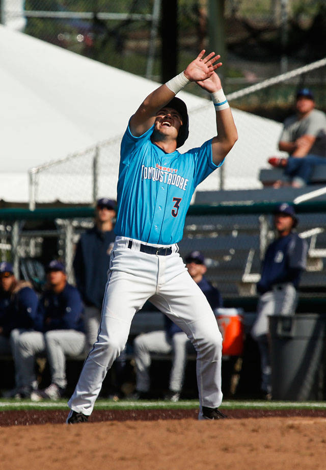 The Aquasox’ Bobby Honeyman uses his hands to block the sun while looking for the ball as he waits to run during Sunday’s game at Everett Memorial Stadium. (Andy Bronson / The Herald)