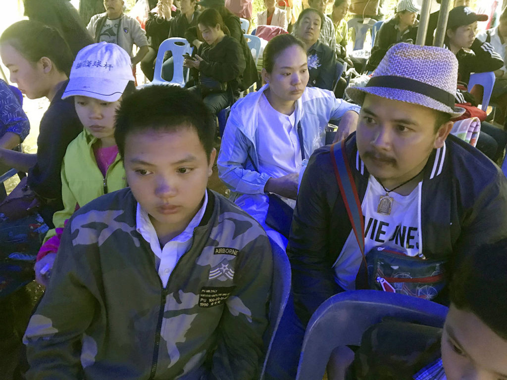 Songpol Kanthawong, 13, sits with his father, Noppadon Kanthawong (right), in a tent for families and friends to wait for news outside the cave where his soccer team and coach went missing in Mae Sai, Chiang Rai province, Northern Thailand, on Tuesday. Songpol is a member of the missing team but didn’t join them on the trip. (AP Photo/Tassanee Vejpongsa)
