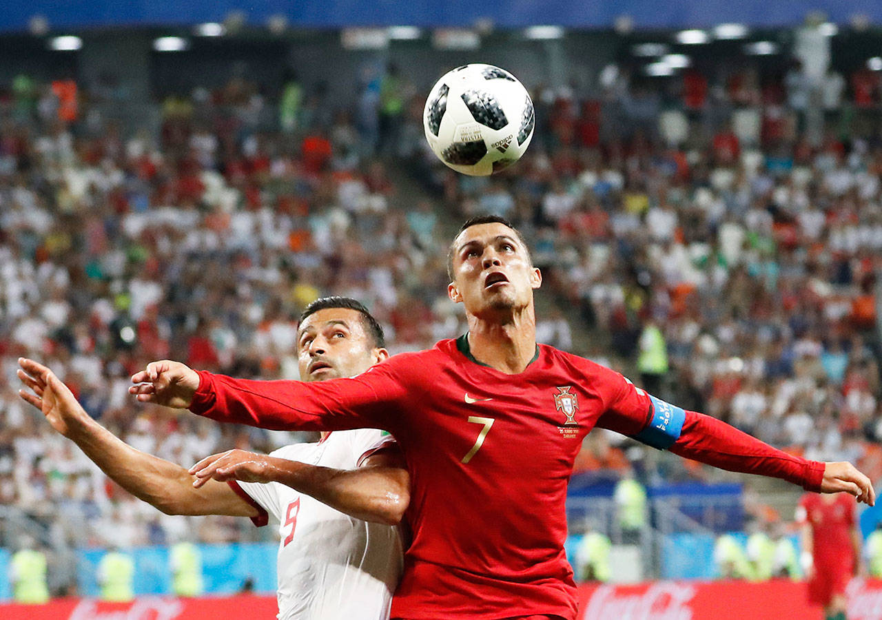 Portugal’s Cristiano Ronaldo (right) and Iran’s Omid Ebrahimi challenge for the ball during the group B match Monday between Iran and Portugal at the 2018 World Cup at the Mordovia Arena in Saransk, Russia. (Pavel Golovkin / Associated Press)