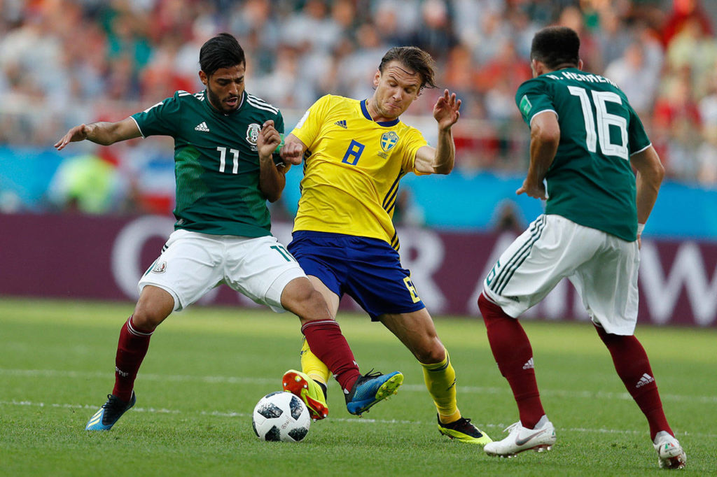 Mexico’s Carlos Vela (left) and Sweden’s Albin Ekdal (center) challenge for the ball during the group F match Wednesday between Mexico and Sweden, at the 2018 World Cup at Yekaterinburg Arena in Yekaterinburg, Russia. (Eduardo Verdugo / Associated Press)
