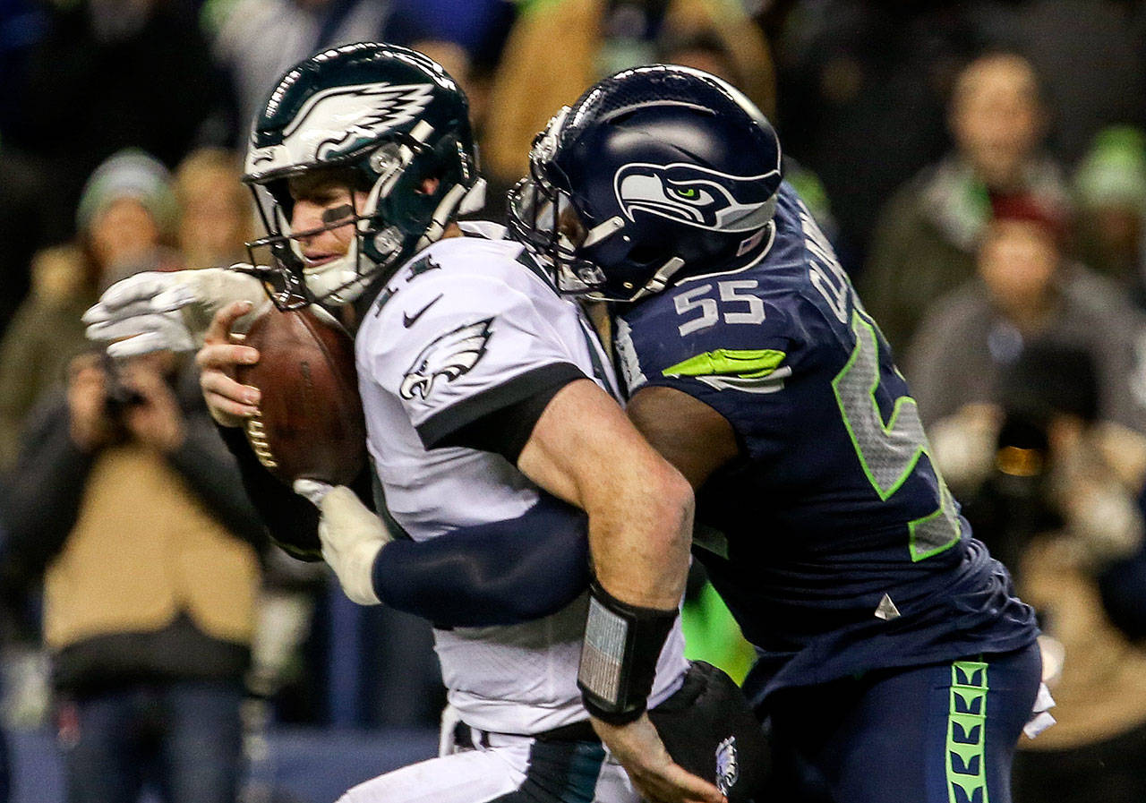 Seahawks defensive lineman Frank Clark (right) sacks Eagles quarterback Carson Wentz during a game on Dec. 3, 2017, in Seattle. (Kevin Clark / The Herald)