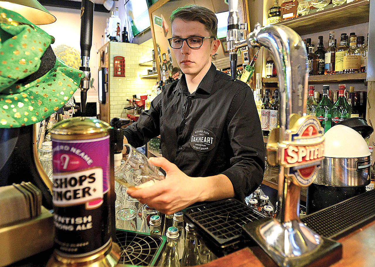 Bartender Mateusz Molenda fills a glass of beer in a British pub in Warsaw, Poland, in 2017. Bartenders, not concierges, often know the full scoop on a city’s “hot” and “not” spots. (Alik Keplicz/AP)