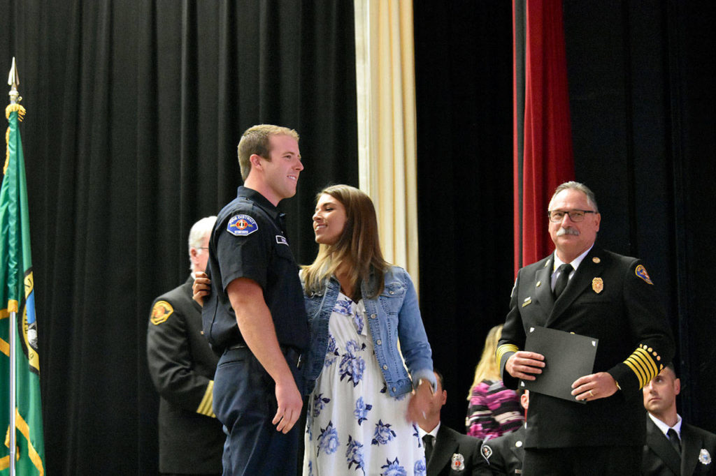 Jamie Dowell looks closely at a pin she placed on her husband, Cory Dowell, at his graduation from Snohomish County’s first fire academy on June 27. (Caleb Hutton / The Herald)
